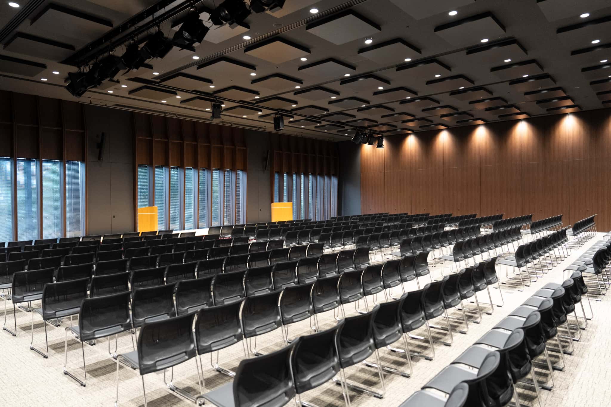 大手町プレイス ホール&カンファレンスの建物外観のローアングルビュー。ガラス張りの高層ビルと張り出した中層部を白い円柱列が支えており、建物入口前の広場には緑豊かな植栽と案内板が設置されている。